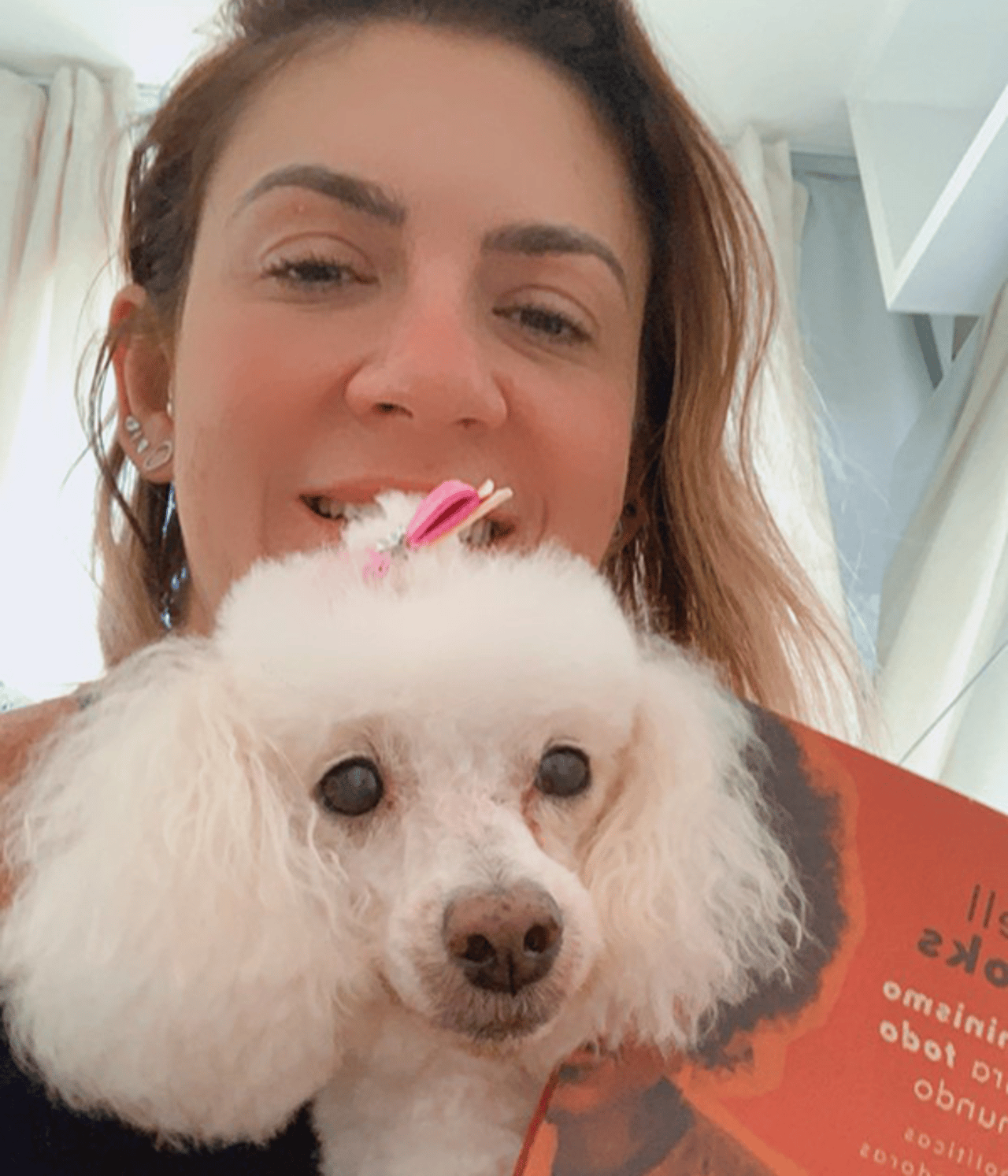 Vanessa está sorrindo com uma cachorra poddle no colo