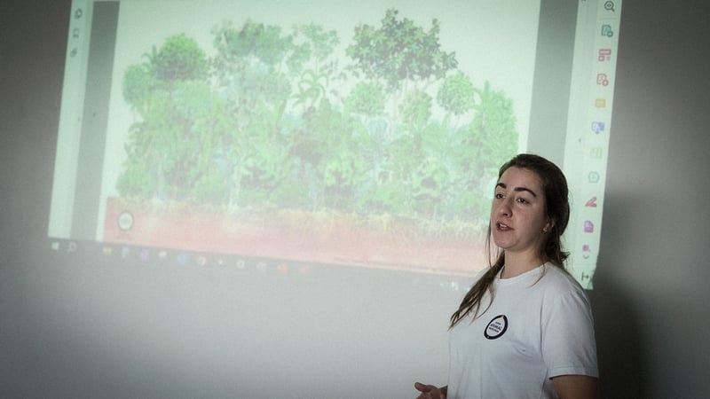 Julia Daumas Trevisan, Analista de Vida Silvestre na Proteção Animal Mundial, está na frente de uma projeção durante sua fala no evento Diálogos Amazônicos. Julia está de cabelo preso e camiseta branca da Proteção Animal Mundial.