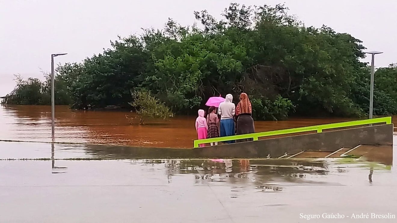 mudanças climáticas: imagem de pessoas tentando se mover na cidade alagada no Rio Grande do Sul.