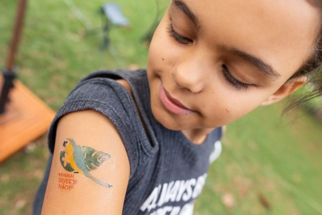 Imagem de uma criança com tatuagem fake de animal silvestre no braço