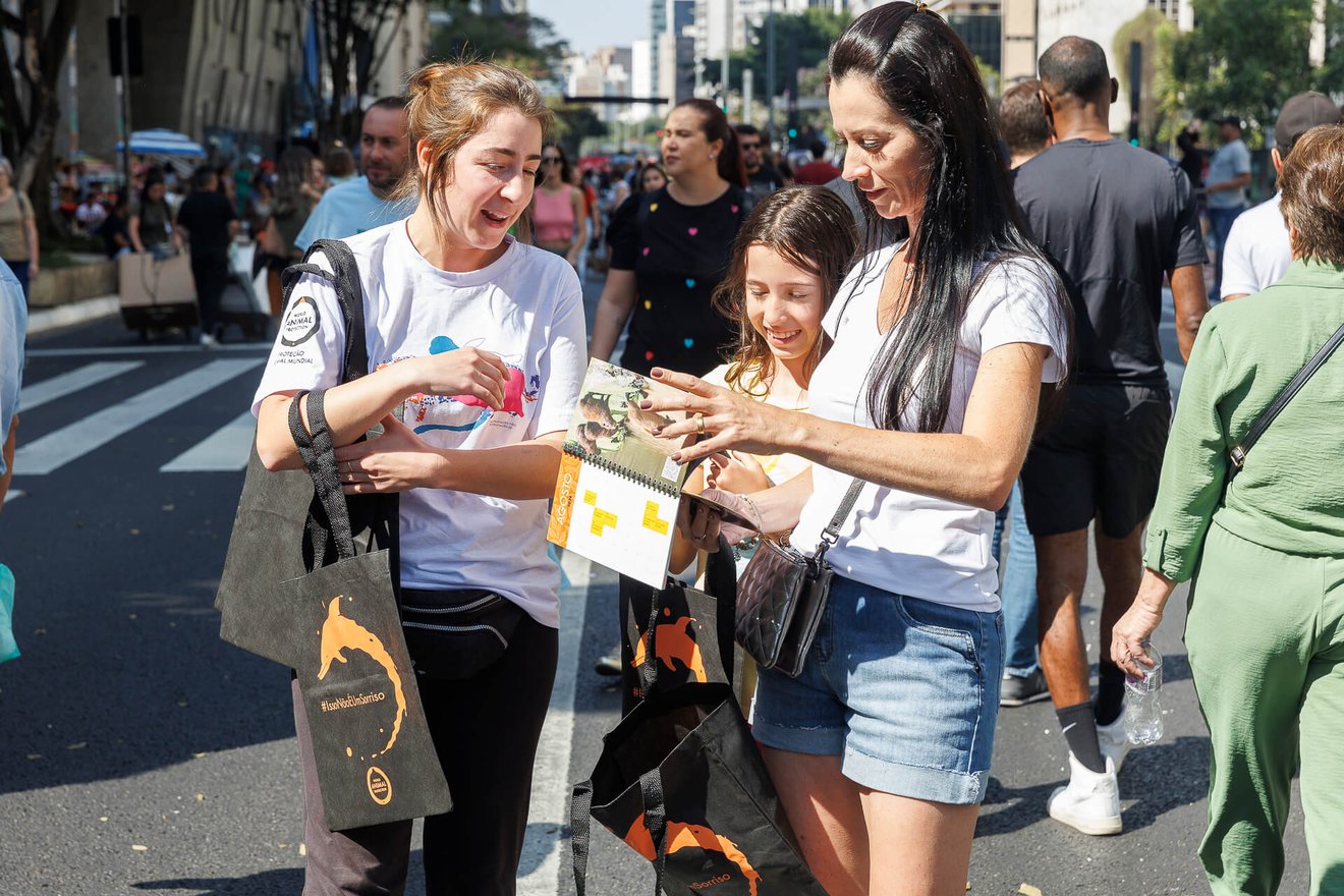 Imagem de uma representante da Proteção Animal Mundial conversando com pessoas na avenida Paulista