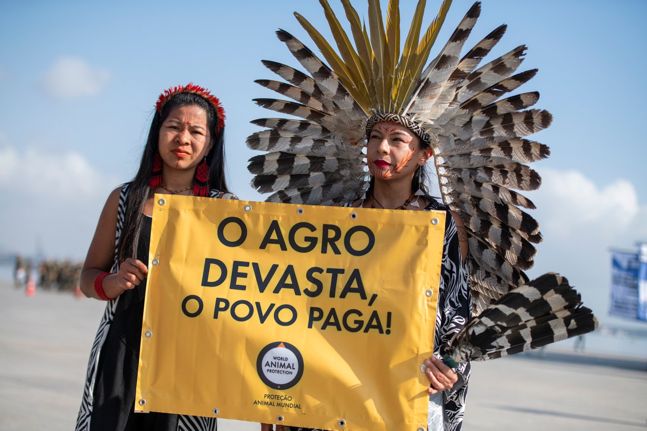 Influenciadora indígena Daiara Tukano segura nosso banner com o dizer "O agro devasta, o povo paga"