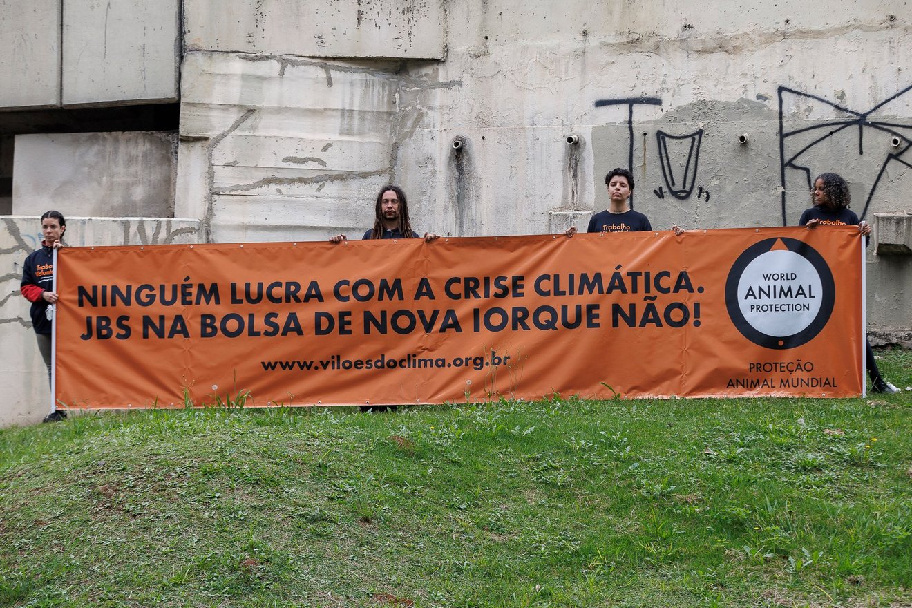 Quatro ativistas seguram banner na Marginal Tietê com os dizeres "Ninguém lucra com a crise climática. JBS na Bolsa de Nova Iorque NÃO!"