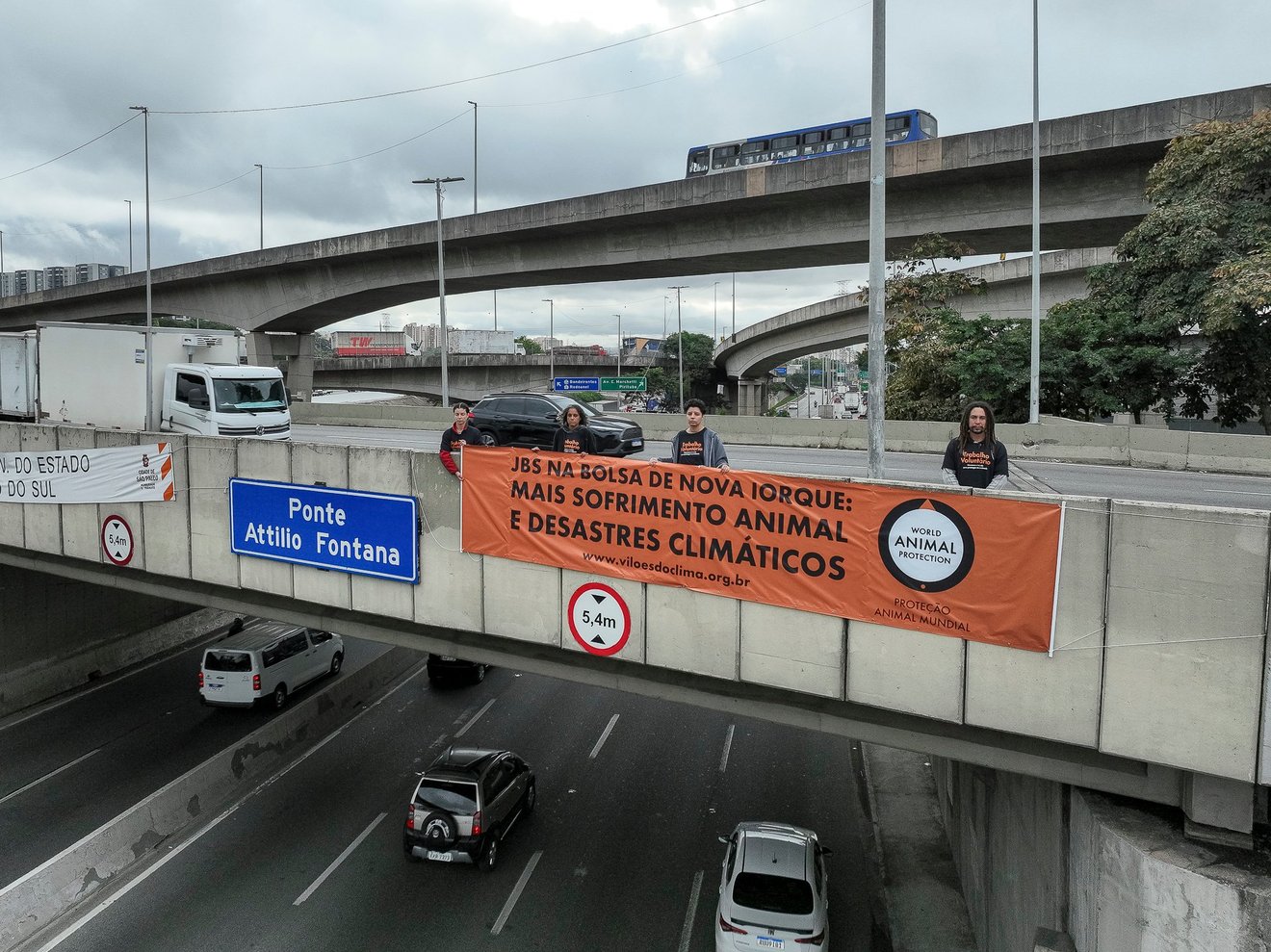 Ativistas em cima da Ponte Atílio Fontana, na Marginal Tietê, seguram banner com dizer "JBS na Bolsa de Nova Iorque: Mais sofrimento animal e desastres climáticos"