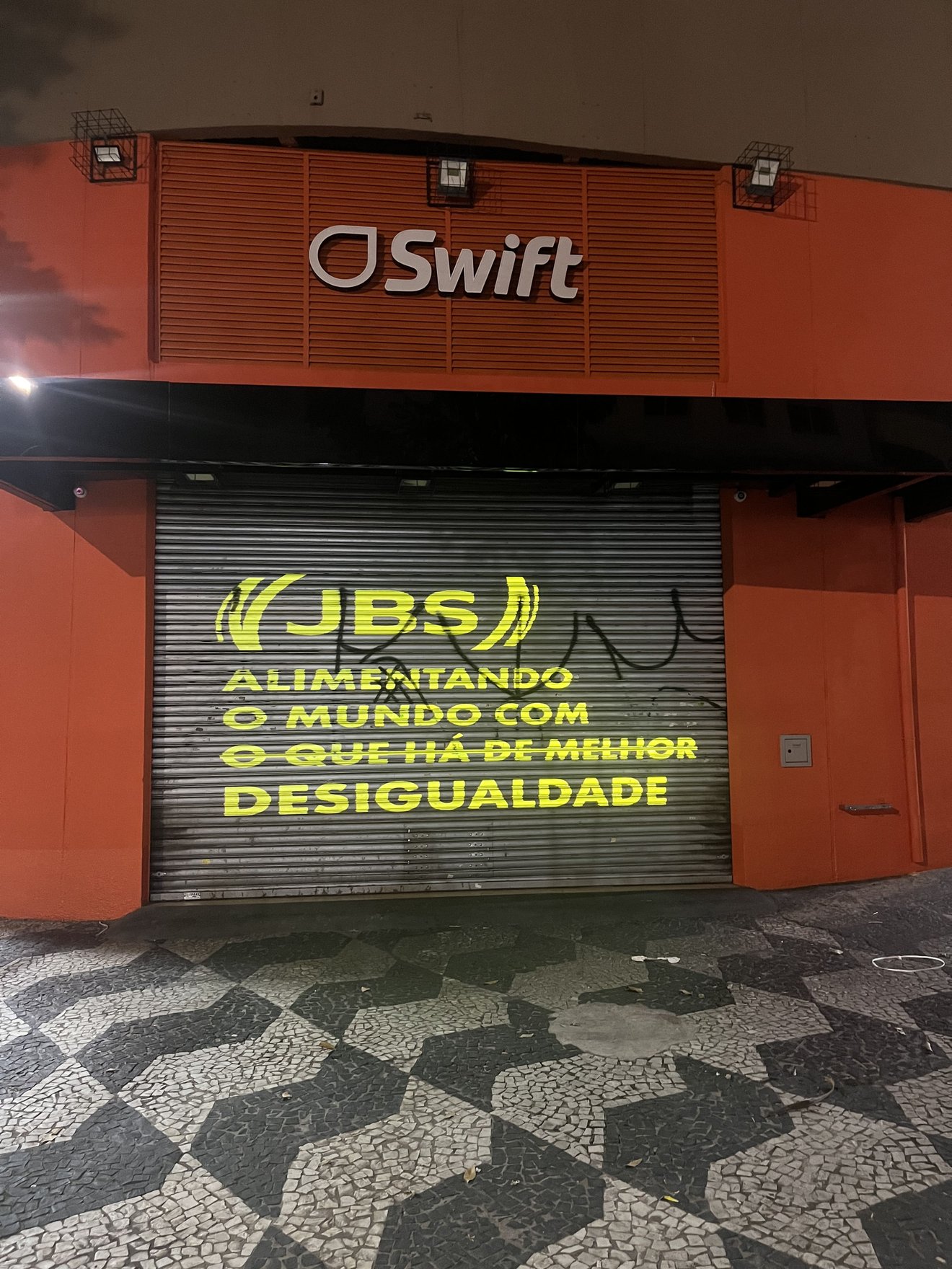 Projeção com a frase "JBS - Alimentando o mundo com desigualdade"