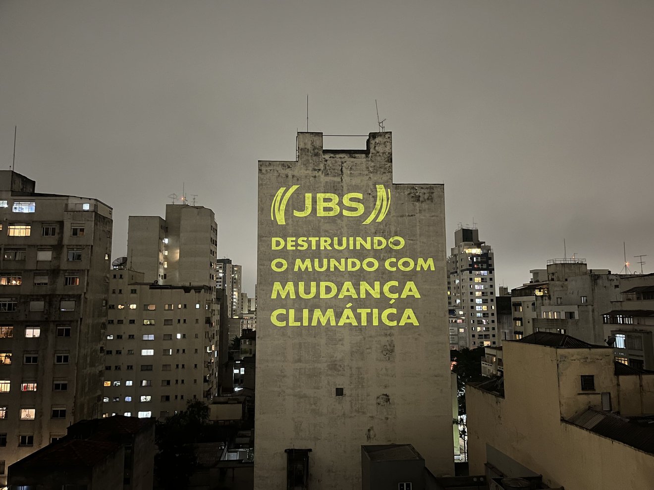 Projeção com a frase "JBS - Destruindo o mundo com mudança climática"