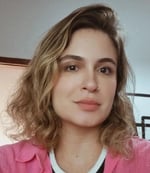 Renata Itaborahy é uma mulher branca, loira, com cabelos na altura do ombro e olhos castanhos. Ela tem um piercing no nariz e está com uma camisa rosa, olhando para a câmera, sem sorrir.