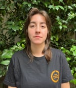 Julia Trevisan é uma mulher branca, de cabelos castanhos claros liso. Ela está olhando para a câmera sem sorrir.