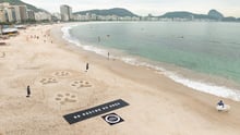 Vista aérea de esculturas em forma de pegadas de onça na Praia de Copacabana