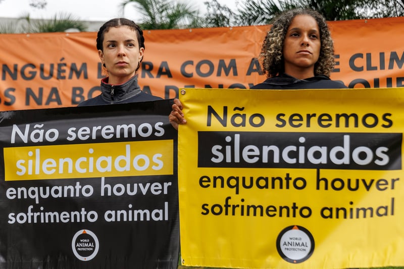 Duas ativistas seguram banners com a frase "Não seremos silenciados enquanto houver sofrimento animal".